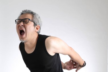 Beyaz arka planda duran spor üniformalı yaşlı Asyalı adam..