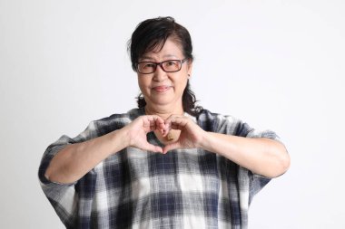 Beyaz arka planda duran yaşlı Asyalı kadın..