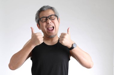 Beyaz arka planda duran spor üniformalı yaşlı Asyalı adam..