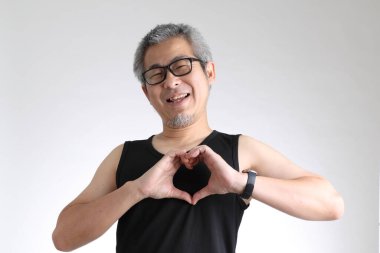 Beyaz arka planda duran spor üniformalı yaşlı Asyalı adam..