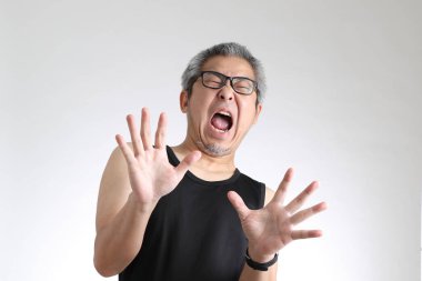 Beyaz arka planda duran spor üniformalı yaşlı Asyalı adam..