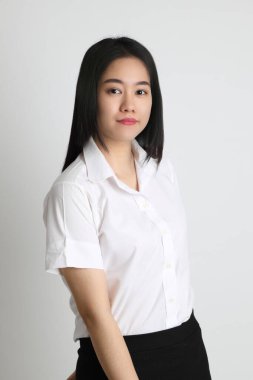 Üniversite üniformalı Asyalı kız beyaz arka planda duruyor..