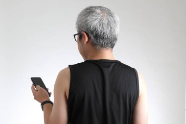 Beyaz arka planda duran spor üniformalı yaşlı Asyalı adam..