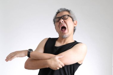 Beyaz arka planda duran spor üniformalı yaşlı Asyalı adam..