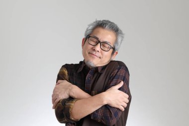 Beyaz arka planda duran kıdemli Asyalı adam.