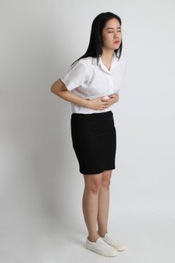 Üniversite üniformalı Asyalı kız beyaz arka planda duruyor..