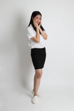 Üniversite üniformalı Asyalı kız beyaz arka planda duruyor..