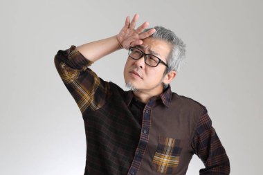 Beyaz arka planda duran kıdemli Asyalı adam.