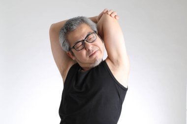 Beyaz arka planda duran spor üniformalı yaşlı Asyalı adam..