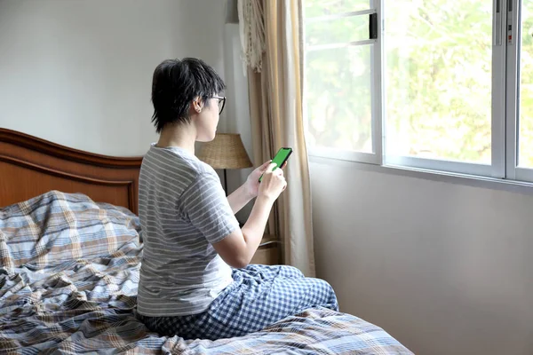 那个在床上用智能手机的亚洲女人 — 图库照片