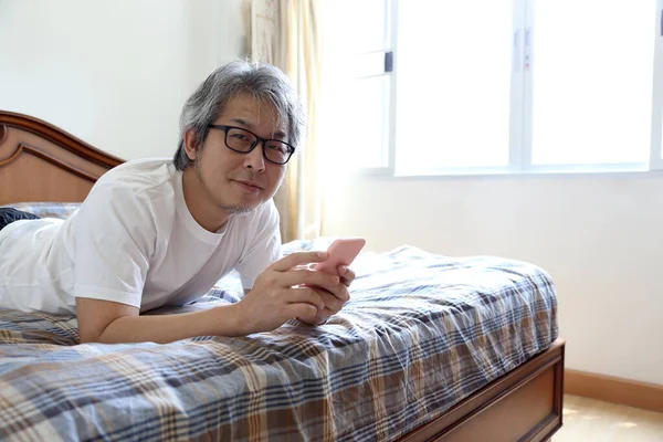 Uomo Asiatico Utilizzando Smart Phone Sul Letto — Foto Stock