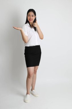 Üniversite üniformalı Asyalı kız beyaz arka planda duruyor..