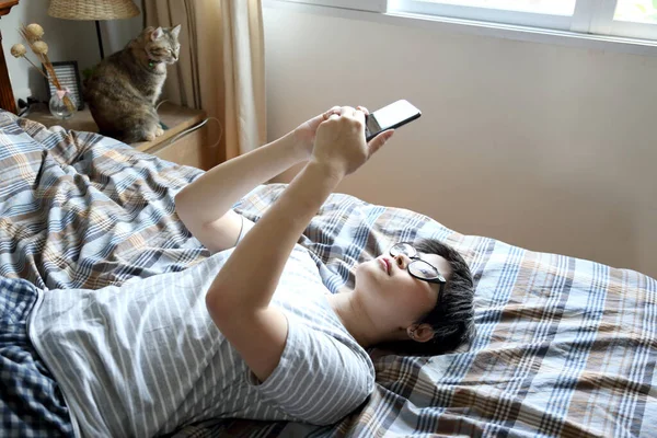 那个在床上用智能手机的亚洲女人 — 图库照片