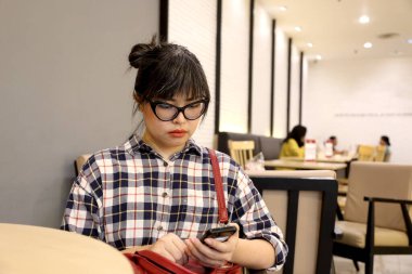 Kafede akıllı telefon kullanan Asyalı kadın..