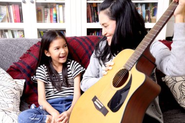 Asyalı anne çocuğuna gitar çalmayı öğretiyor..