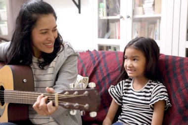 Asyalı anne çocuğuna gitar çalmayı öğretiyor..