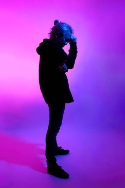 Beyaz arka planda jel renkli ışıkla poz veren Asyalı adam..