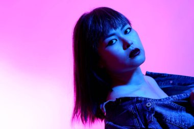 Beyaz arka planda jel renkli ışıkla poz veren Asyalı kadın..