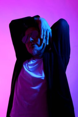 Beyaz arka planda jel renkli ışıkla poz veren Asyalı adam..