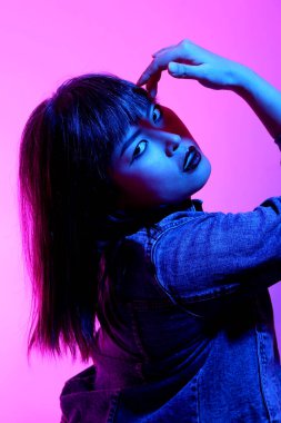 Beyaz arka planda jel renkli ışıkla poz veren Asyalı kadın..