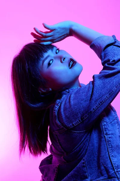 Beyaz arka planda jel renkli ışıkla poz veren Asyalı kadın..