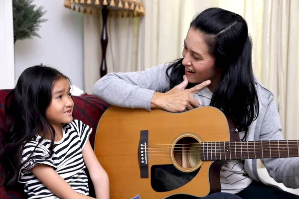 Asyalı anne çocuğuna gitar çalmayı öğretiyor..