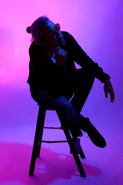 Азиатский мужчина позирует на белом фоне с гелевым цветом света.