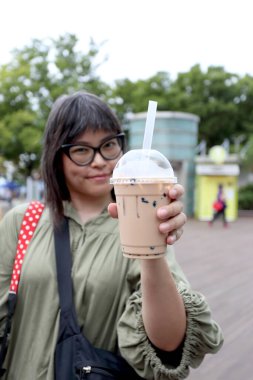 Asyalı kadın köpüklü çay gösteriyor..