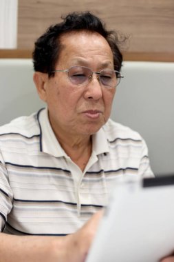 Tablet kullanan Asyalı yaşlı adam..