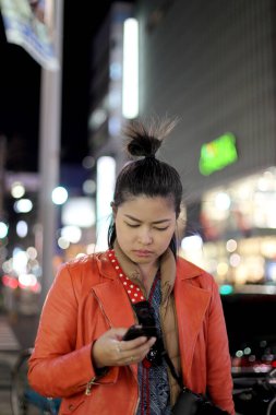 Gece büyük şehirde akıllı telefon kullanan Asyalı kadın..