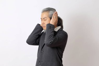 Asyalı adam beyaz arka planda kulaklarını kapatıyor..