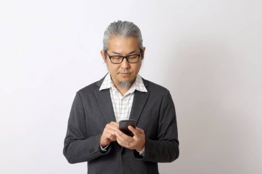 Asyalı işadamı beyaz arka planda akıllı telefon tutuyor..