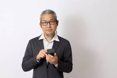 Asyalı işadamı beyaz arka planda akıllı telefon tutuyor..