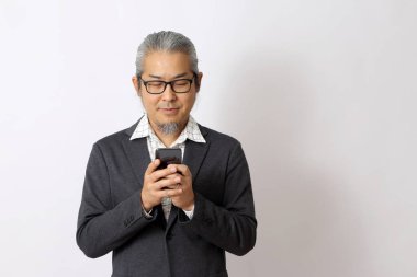 Asyalı işadamı beyaz arka planda akıllı telefon tutuyor..