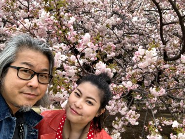 Kiraz ağaçlarının altında poz veren Asyalı çift..