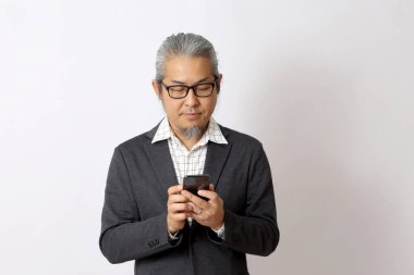 Asyalı işadamı beyaz arka planda akıllı telefon tutuyor..