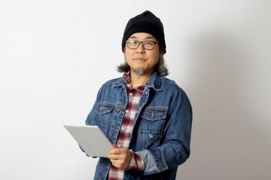 Beyaz arka planda duran kot gömlekli ve bereli Asyalı adam..