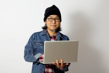 Beyaz arka planda duran kot gömlekli ve bereli Asyalı adam..