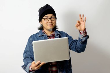 Beyaz arka planda duran kot gömlekli ve bereli Asyalı adam..