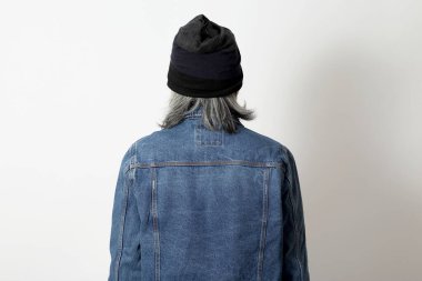 Beyaz arka planda duran kot gömlekli ve bereli Asyalı adam..