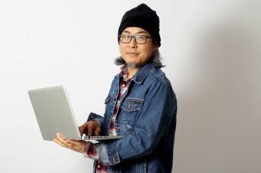 Beyaz arka planda duran kot gömlekli ve bereli Asyalı adam..