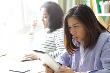 Tablet üzerinde çalışan Asyalı kadınlar..