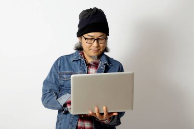 Beyaz arka planda duran kot gömlekli ve bereli Asyalı adam..