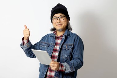 Beyaz arka planda duran kot gömlekli ve bereli Asyalı adam..