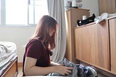 Güneydoğu Asyalı bir kadın çamaşırhane için beyaz elbiselerden renkli giysileri ayırıyor..