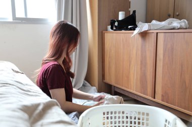 Güneydoğu Asyalı bir kadın çamaşırhane için beyaz elbiselerden renkli giysileri ayırıyor..