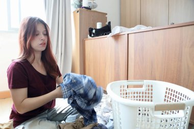 Güneydoğu Asyalı bir kadın çamaşırhane için beyaz elbiselerden renkli giysileri ayırıyor..