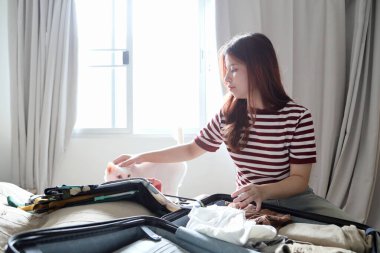 Güneydoğu Asyalı bir kadın giysilerini bavula koyuyor..