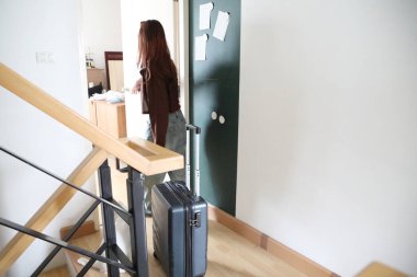 Güneydoğu Asyalı bir kadın bavulunu odasının önüne taşıyor..