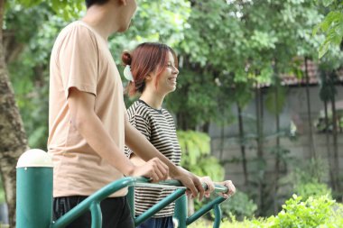 Güneydoğu Asyalı bir kadının bir arkadaşı onu karşılamaya geliyor ve antrenmana başka bir egzersiz makinesiyle katılıyor. 